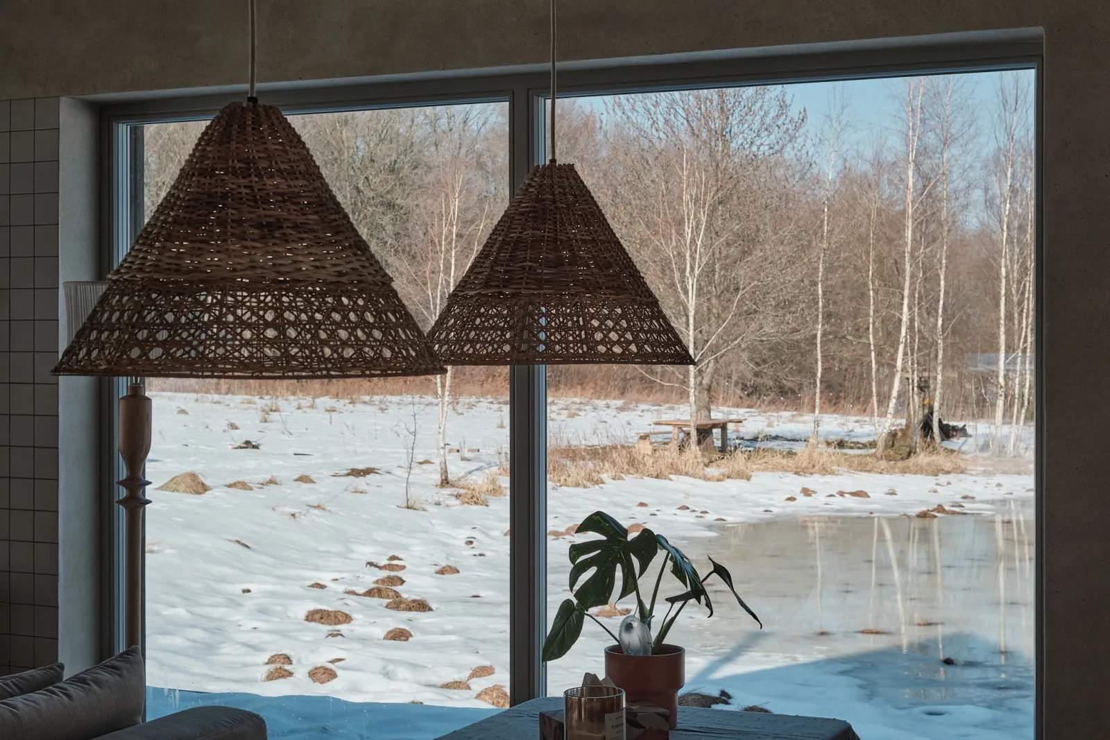 View from Salinko's living room through a panoramic window onto the snowy meadow and pond